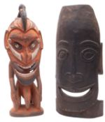 A carved and stained wooden African figure with pierced nose and bird head dress,
