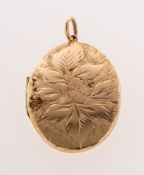 An oval locket pendant, the front panel having floral and foliate carving on a textured background,