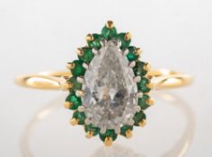 A pear-shaped diamond and emerald ring, claw set to the centre with a pear-shaped diamond,