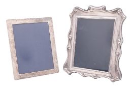 Two modern silver mounted photograph frames, one shaped rectangular with a scroll border,