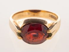 A 9ct gold garnet dress ring, claw set east to west with an oval-cut garnet, UK hallmark, size M1/2,