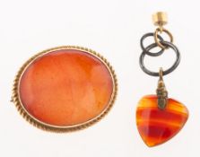 An orange glass brooch and carnelian heart charm,