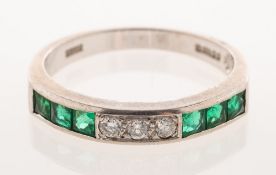 An emerald and diamond half eternity ring, channel set with a row of three square-cut emeralds,