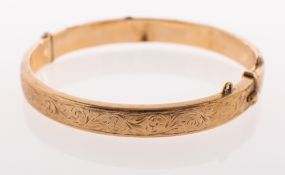 A 9ct gold hinged bangle, with foliate carving to one section, push in clasp, safety chain missing,