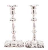 A pair of early Victorian silver candlesticks, on shaped square bases (loaded),