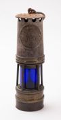 An early 20th Century Ackroyd and Best miner's lamp, of steel and brass with blue glass shade,