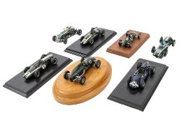 A group of seven built white metal Cooper racing cars, five mounted on display plinths,