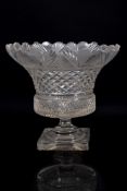 A clear glass pedestal vase of flaring form with notched rim cut with fret and hobnail bands,