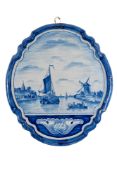 A Dutch Delft plaque of shield shaped form painted in blue with a landscape, 60cm tall.