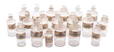 A mixed group of clear glass apothecary bottles and stoppers each with gilt and black banner,