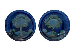 A pair of William Moorcroft pottery plates each tube lined in the Moonlit Blue landscape pattern,