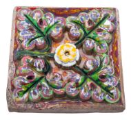 A Tamar Works terracotta tile of square form moulded in high relief with flowers and foliage,