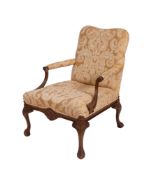 A carved beech wood open armchair of Gainsborough type, with a cartouche shaped stuff-over back,
