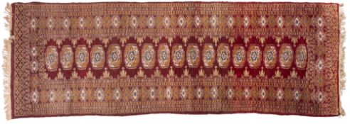 An Afghan Turkoman runner, the brick red field with a row of quartered guls,
