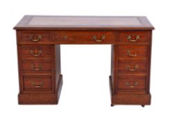 An Edwardian walnut twin pedestal desk, the moulded top inset with a panel of tooled leather,