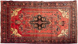 A Malayer rug, the brick red field with a geometric medallion,