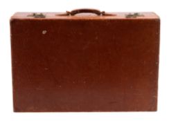 Cartier, a tan leather suitcase, early 20th century; with twin brass clasps flanking the handle,