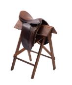 A 20th Century leather 17,5' saddle, together with a pine folding saddle rack, 81cm high, 70cm long.
