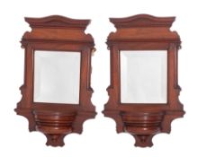A pair of Edwardian mahogany framed wall mirrors, with arched moulded cornice,
