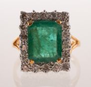 An 18ct gold emerald and diamond cluster ring, of rectangular form,