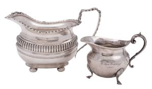 An Edwardian silver milk jug, with a gadroon & husk border, a fluted frieze and on bun feet,