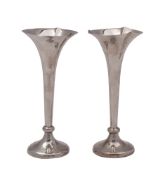 A pair of early 20th century silver spill vases, the shaped capitals with serrated borders,