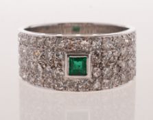 A diamond and emerald ring, of wide band form,