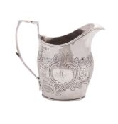 A George III silver milk jug, helmet-shaped, with an angular handle and chased in the Rococo manner,