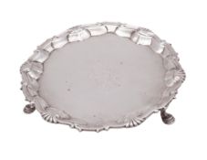 A George II silver waiter, of shaped circular outline, with a husk & scroll border,