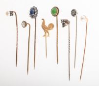 A collection of stick pins, including a stick pin claw set with an oval sapphire cabochon,