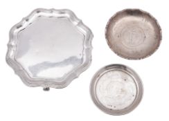 A George V silver waiter, of shaped circular outline, with a reeded border and on three scroll feet,