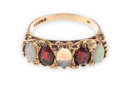 A 9ct gold 1970's opal and garnet ring, grain set with three oval-cut opal cabochons,