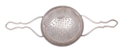 A George III Irish silver lemon strainer, with twin wire-work handles and a beaded border,