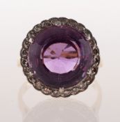 An amethyst and diamond cluster ring, claw set with a circular mixed-cut amethyst, measuring approx.
