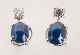 A pair of cabochon sapphire and diamond earrings, each claw set with an oval-cut sapphire cabochon,