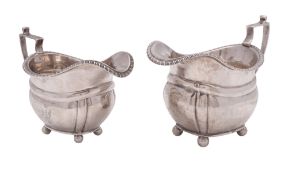A George V graduated pair of silver milk jugs, with gadroon borders,