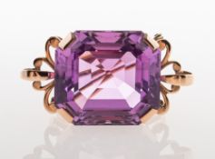 A large decorative brooch, claw set with an octagonal step-cut vibrant pink stone,