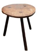 An elm cricket table, 18th Century, the circular top on three splayed legs; 62cm high,