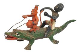 A cold painted figure of Mephistopheles and a young boy riding a crocodile,