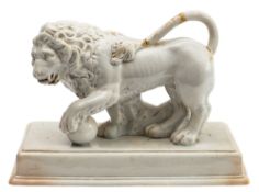 A pearl ware figure of the Medici lion stood with raised tail and one paw resting on a ball,