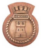 A bronze ship's badge for HMS 'Newcastle' on a teak mount, 26cm high.