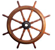 A teak and brass ship's helm, the iron boss radiating block and turned spars with brass banding,