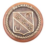 A French brass ship's badge 'Du Chayla' mounted on a mahogany base, 22.5cm diameter.