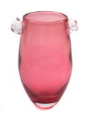 A studio glass vase, the cranberry slender oviform body with clear 'swirl' handles, 14cm high,