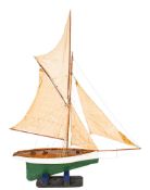 An early 20th century pond yacht, fully rigged over simulated plank deck with fittings,