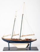 A scale model of a sailing yacht, running rigged with furled sails over planked deck with fittings,