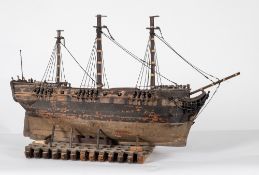 A 19th century model of a Royal Navy ship, part rigged over decks with open gun ports with guns,