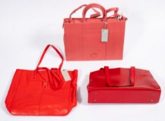 A group of three Radley leather handbags. Comprising two in red and one in pink with a dustbag.