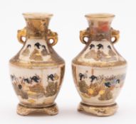 A pair of Japanese Satsuma earthenware two handled vases each decorated with panels containing