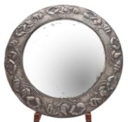 A repousse metal framed convex wall mirror in Art Nouveau style,